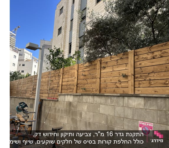 גדר עץ מותקנת ליד בניין עם כלי עבודה